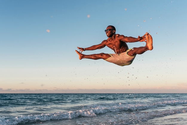 Jovem pulando na praia. atitude feliz.