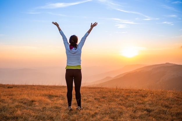 Jovem pulando nas montanhas do pôr do sol