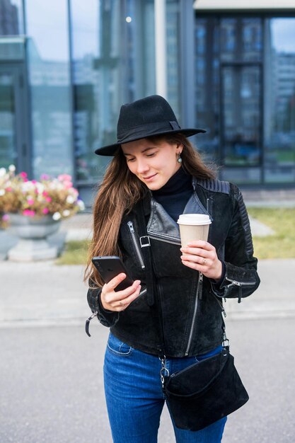 Jovem que fica com smartphone e café na frente do escritório.