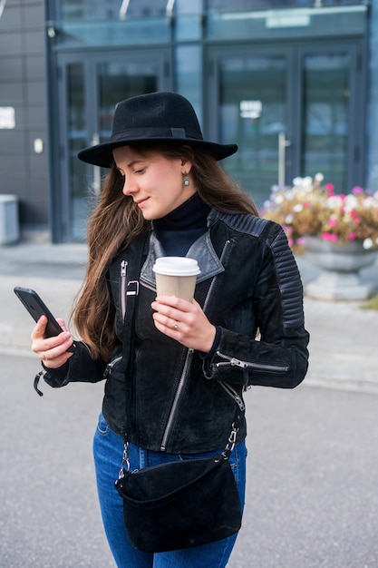 Jovem que fica com smartphone e café na frente do escritório.