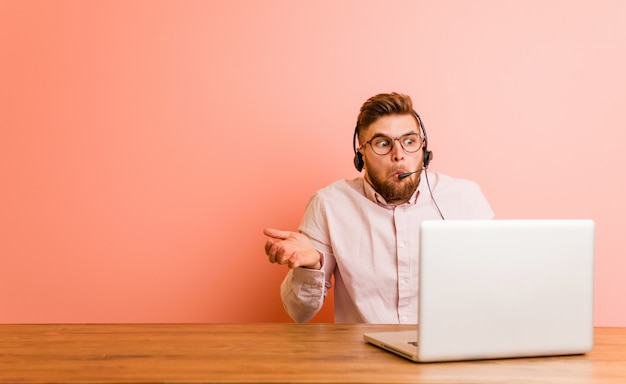 Jovem que trabalha em um call center encolhe os ombros e abre os olhos confusos.