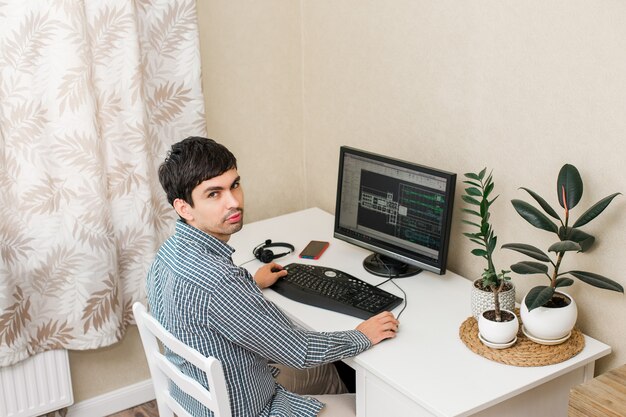 Jovem que trabalha em uma mesa com um computador em seu local de trabalho.