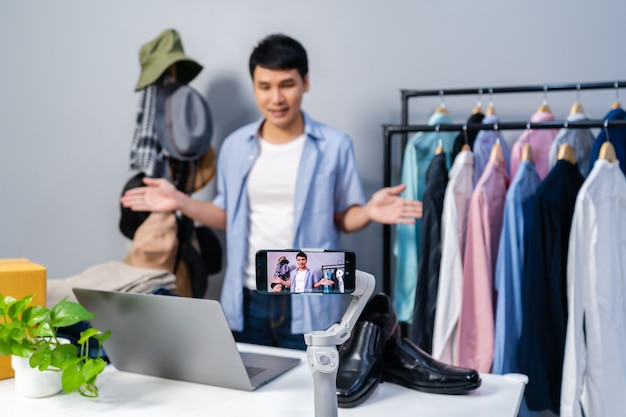 Jovem que vende roupas e acessórios online por streaming ao vivo em smartphone. comércio eletrônico on-line empresarial em casa