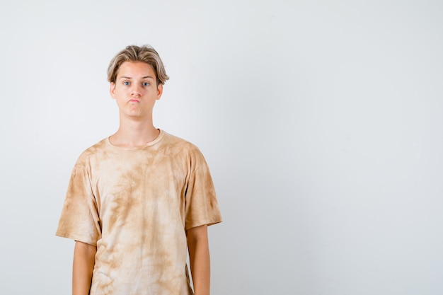 Jovem rapaz adolescente olhando para frente enquanto fazia careta na camiseta e parecendo desapontado. vista frontal.