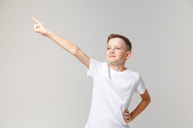 Jovem rapaz bonito fica na pose de um herói, levantando a mão. Motivador