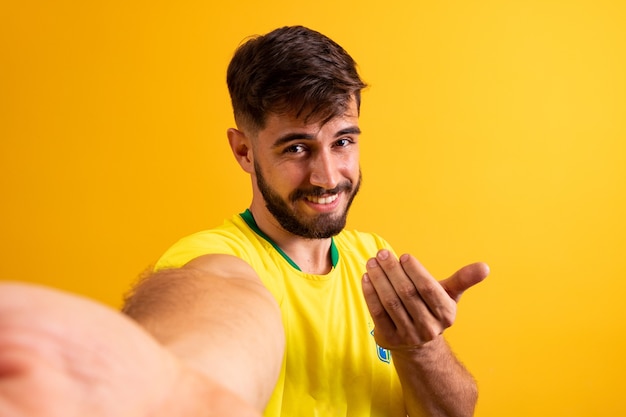 Jovem rapaz bonito vestido para o jogo do Brasil. closeup de homem vestido para a copa do mundo, chamando com a mão