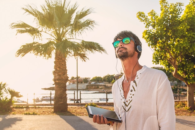 Jovem rapaz de férias usando tablet perto da praia