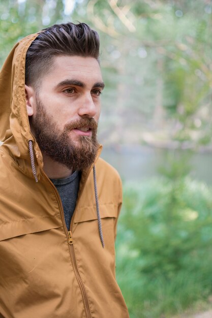 jovem rapaz vestindo uma jaqueta com capuz para se proteger do frio outono