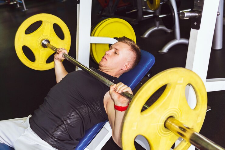 Foto jovem realiza exercícios de supino com barra com barra no peito no ginásio