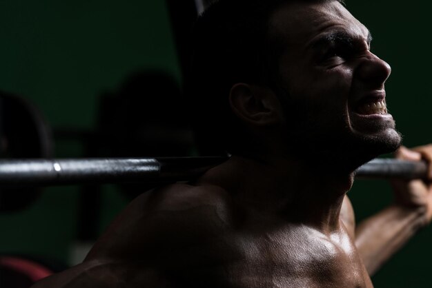 Jovem realizando agachamento com barra um dos melhores exercícios de musculação para pernas