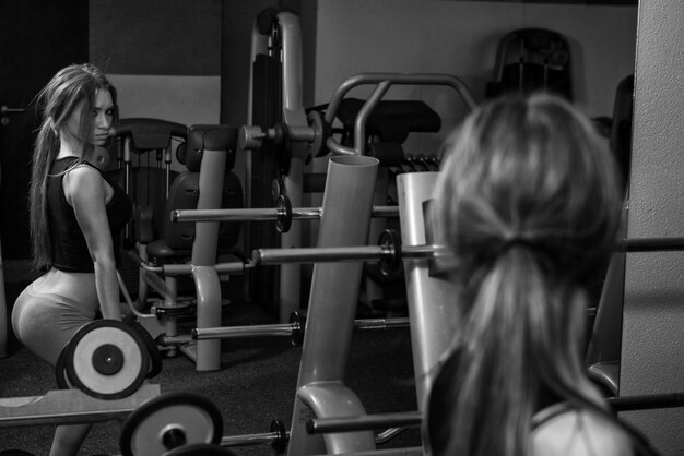 Jovem realizando agachamentos com halteres um dos melhores exercícios de musculação para pernas