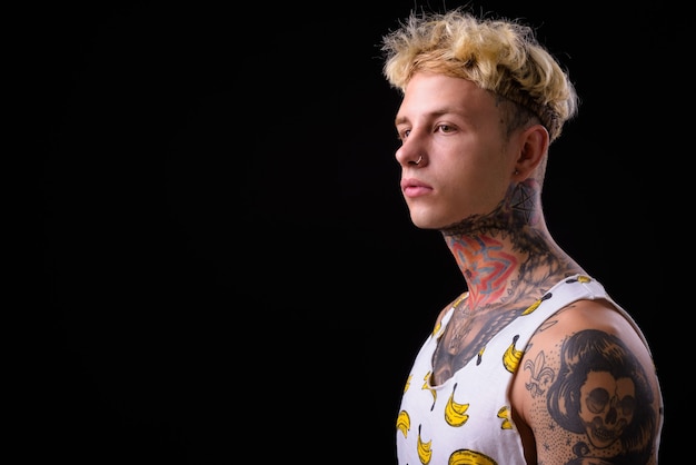 Jovem rebelde bonito com cabelo loiro e tatuagens