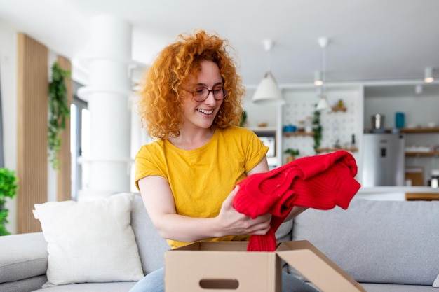 Jovem recebendo encomendas em casa Compras on-line de férias e desembalando a caixa de papelão Serviço de entrega durante a quarentena copiosa Garota feliz recebendo presente Momento de estilo de vida