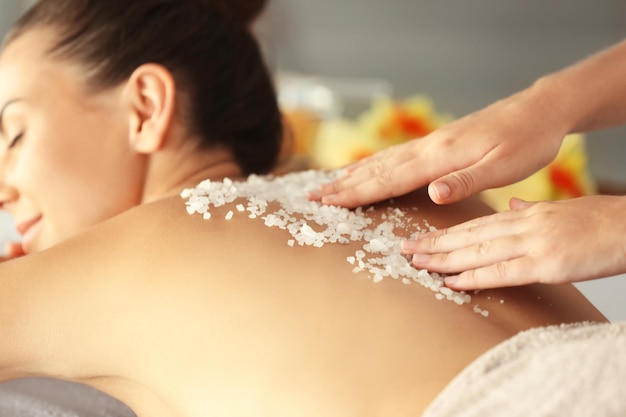 Jovem recebendo massagem com sal marinho no salão spa