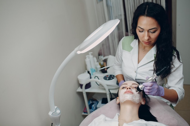 Jovem recebendo massagem facial de elevação de RF elétrica no spa de beleza com equipamento de eletroporação