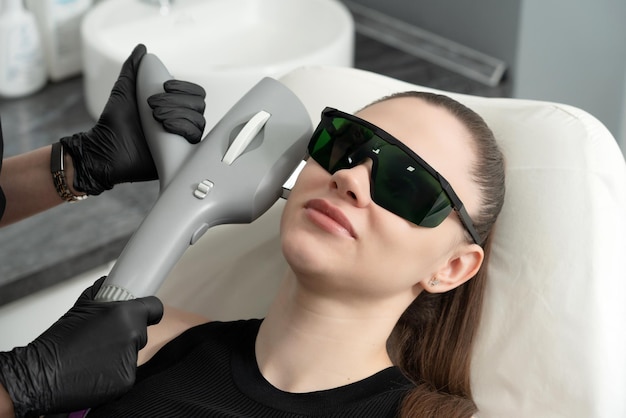 Jovem recebendo tratamento a laser na clínica de cosmetologia