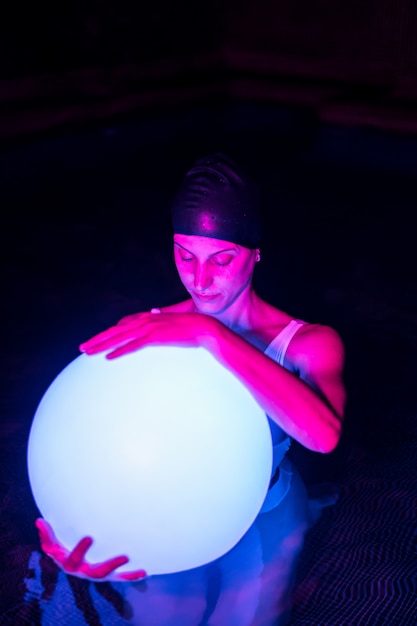 Jovem relaxada na piscina com luz neon