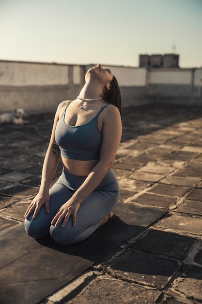 Jovem relaxada praticando ioga em um terraço.