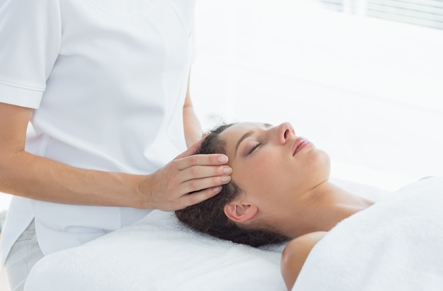 Jovem relaxada, recebendo massagem na cabeça do terapeuta no spa