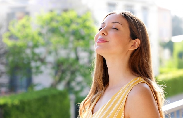 Jovem relaxada respirando ar fresco na varanda pela manhã