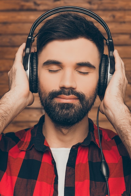 Jovem relaxado usando fones de ouvido ouvindo música com os olhos fechados