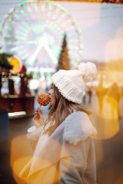 Jovem relaxando bebendo café na feira de Natal festiva, feriados de inverno Luzes ao redor