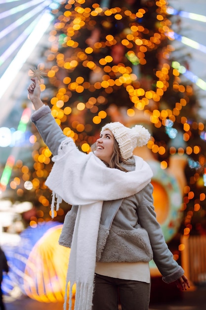 Jovem relaxando bebendo café na feira de Natal festiva, feriados de inverno Luzes ao redor