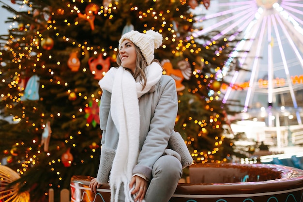 Jovem relaxando bebendo café na feira de Natal festiva, feriados de inverno Luzes ao redor