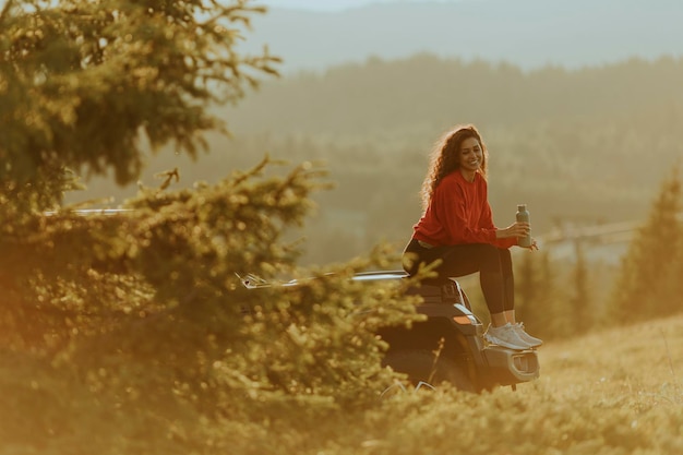 Foto jovem relaxando em um capô de veículo terrestre na zona rural