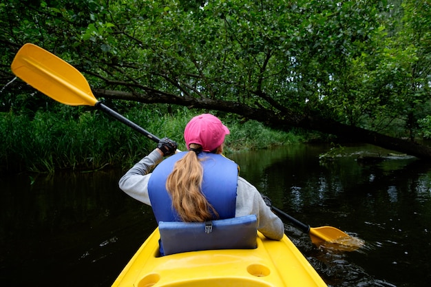 Jovem remar de caiaque sobre o rio, vista por trás