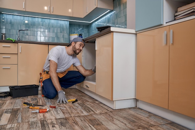 Jovem reparador caucasiano instalando móveis de cozinha