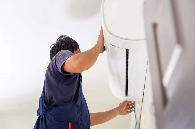 Jovem reparador consertando a unidade de ar condicionado Técnico instalando um ar condicionado na casa de um cliente Conceitos de manutenção e reparo
