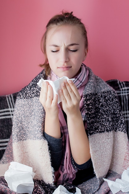 Foto jovem retrato horizontal com um lenço e corrimento nasal no perfil, espirros de gripe, modelo feminino de pele branca na parede rosa. conceito de saúde e médico.