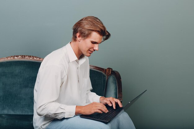 Jovem retrato sentado com o laptop no estúdio.