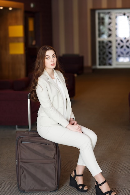 Jovem retrato sentado em malas no terminal ou estação ferroviária, a mulher conheceu em uma viagem.