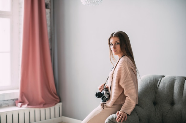 Jovem retrato sorridente mulher com câmera retro em casa. Estilo de vida