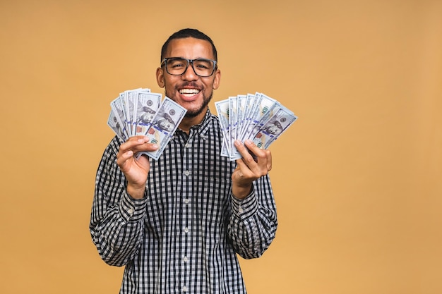 Jovem rico afro-americano em camiseta casual segurando notas de dólar com surpresa