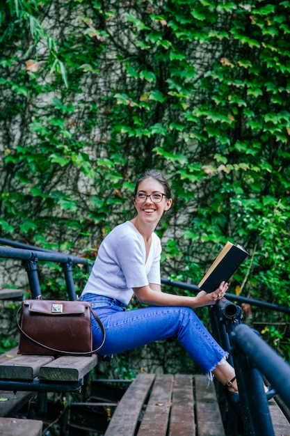 Jovem romântica aprendendo com livros em um banco da faculdade