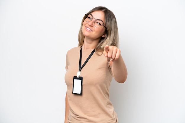 Foto jovem romena com carteira de identidade isolada no fundo branco, apontando para a frente com expressão feliz