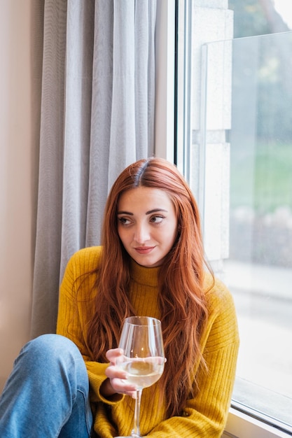 Jovem ruiva bebendo um copo de vinho com uma cara triste Conceito estilo de vida bebida tédio