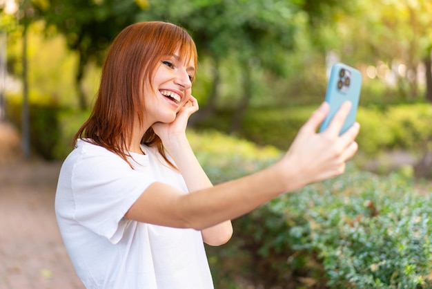 Jovem ruiva bonita ao ar livre usando telefone celular