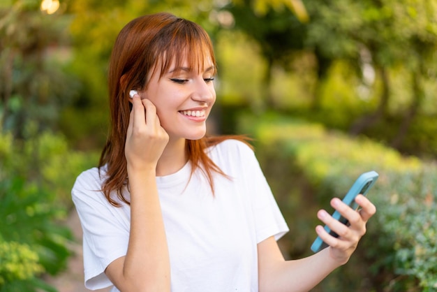 Jovem ruiva bonita ao ar livre usando telefone celular