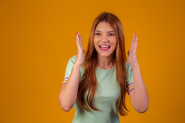 Jovem ruiva chocada e surpresa com fundo amarelo.