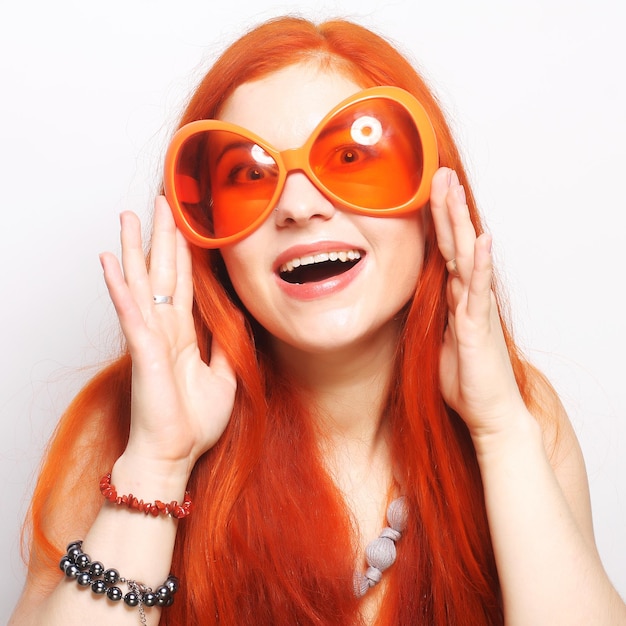 Jovem ruiva engraçada com grandes óculos laranja
