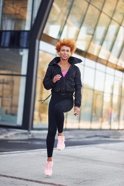 Jovem ruiva europeia em roupas esportivas fazendo fitness ao ar livre