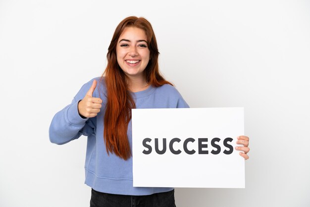 Jovem ruiva isolada em um fundo branco segurando um cartaz com o texto sucesso com o polegar para cima