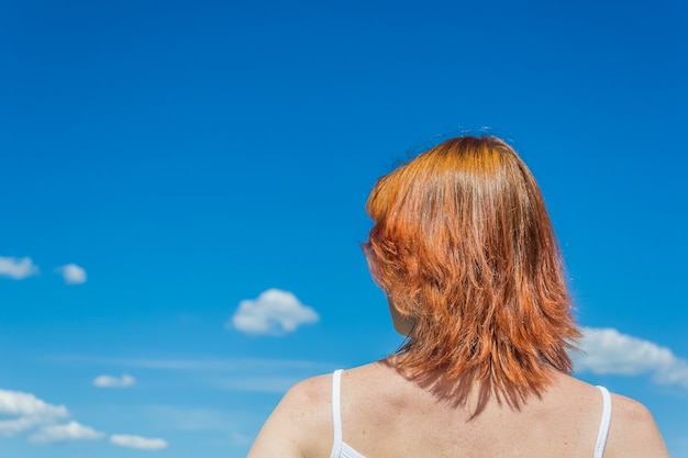 Jovem ruiva olha no céu azul beleza viagens cópia espaço conceito