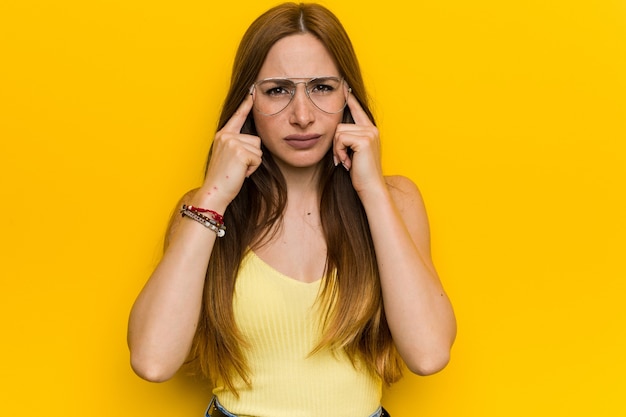 Jovem ruiva ruiva com freckless focada em uma tarefa, mantendo os indicadores apontando a cabeça.