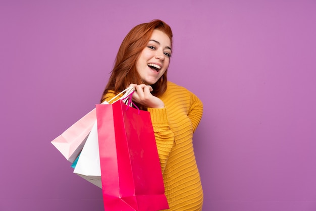 Jovem ruiva segurando sacolas de compras e sorrindo