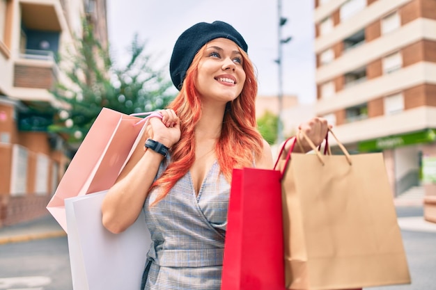 Jovem ruiva vestindo estilo francês segurando sacolas de compras na cidade